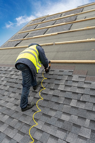 man repairing a shingle roof